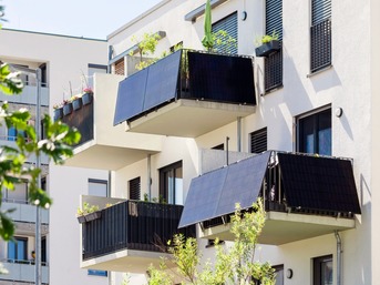 Modernes weißes Mehrfamilienhaus mit Solar-Kollektoren an der Außenseite der Balkone.