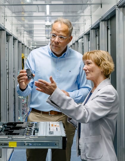 Eine Frau und ein Mann, beides Mitarbeitende der Hamburger Energienetze, unterhalten sich über ein technisches Modul in einem Serverraum.,